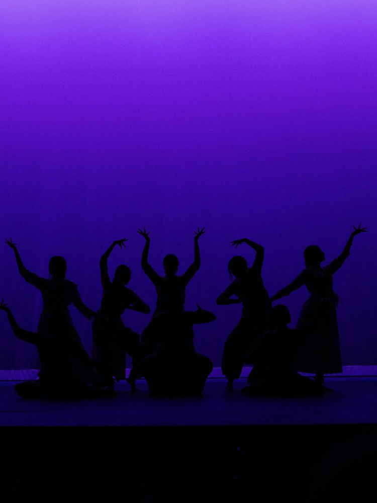 Chak De C'ville dancers performing under purple stage lighting