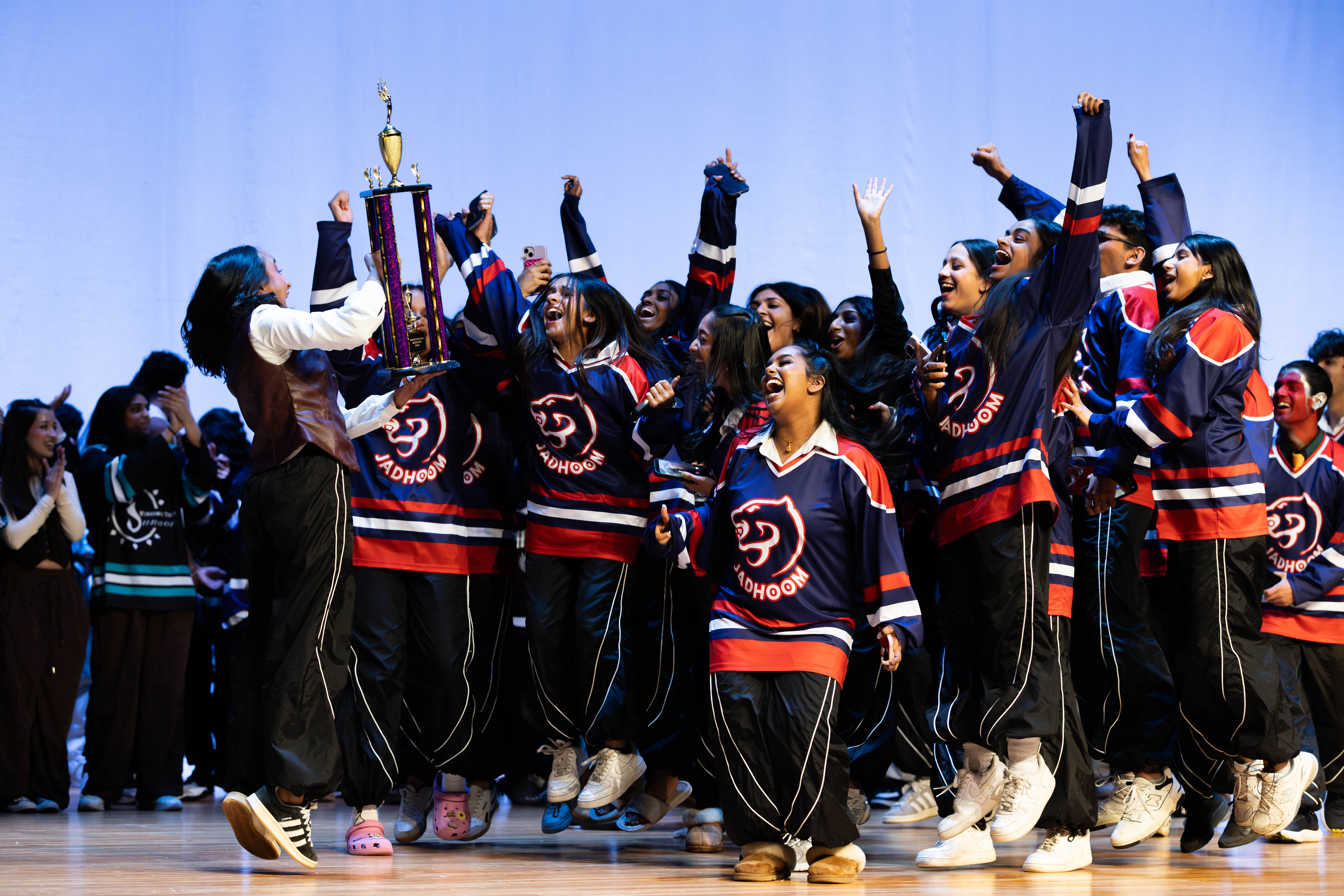 A team celebrates on stage with the competition trophy