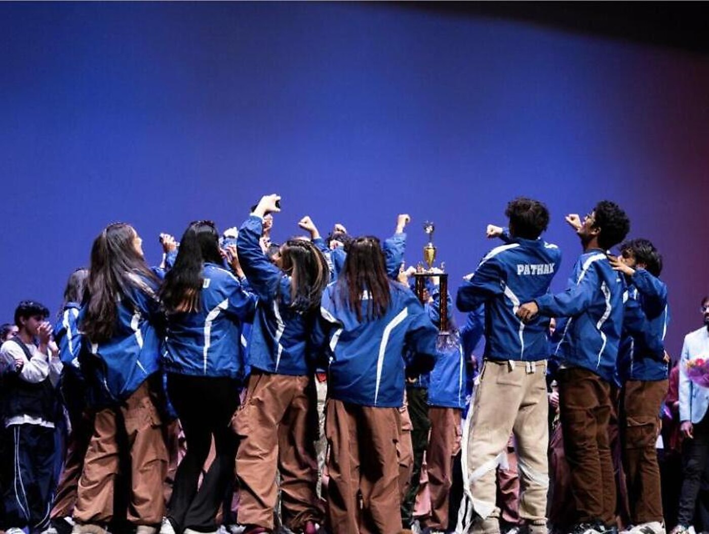 A team celebrates on stage with the competition trophy